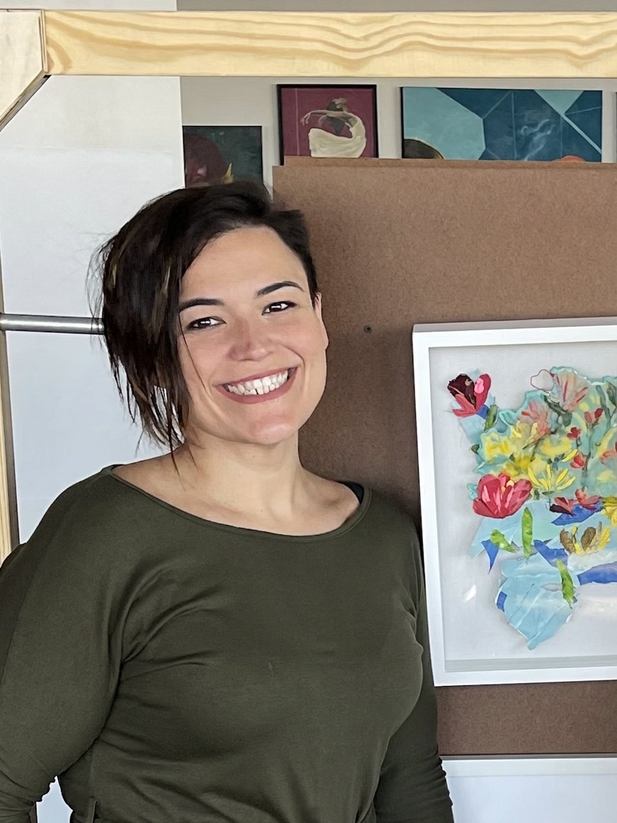 Amber Guinn of Wild Hand in her studio beside a framed floral collage